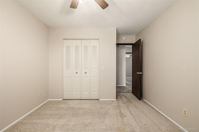 unfurnished bedroom with light carpet, ceiling fan, a closet, and a textured ceiling