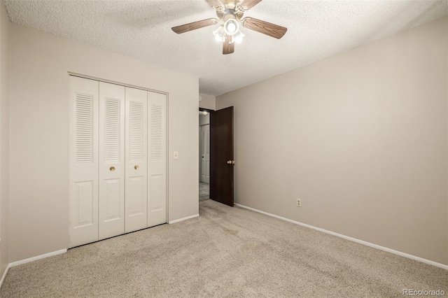 unfurnished bedroom with ceiling fan, light colored carpet, a closet, and a textured ceiling