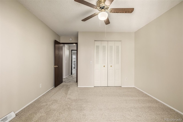 unfurnished bedroom featuring ceiling fan, light colored carpet, a closet, and a textured ceiling