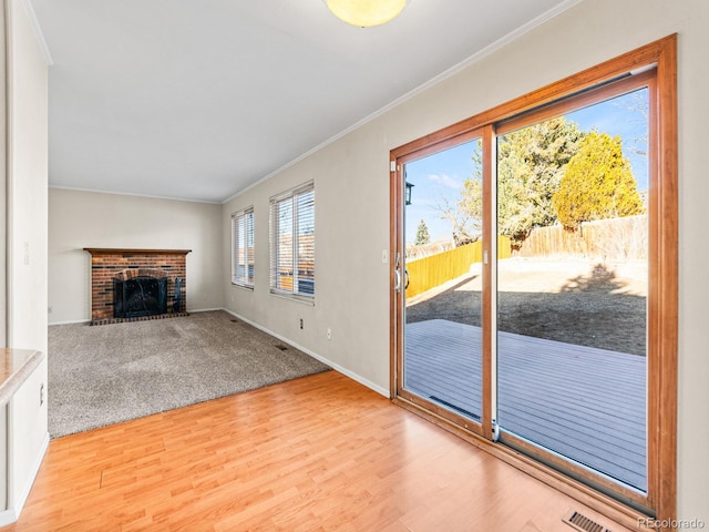 unfurnished living room with crown molding, a fireplace, and light hardwood / wood-style floors