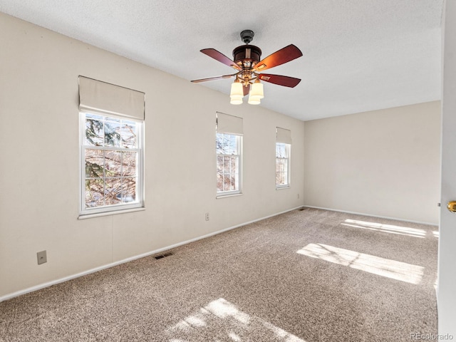 carpeted spare room with ceiling fan and a textured ceiling