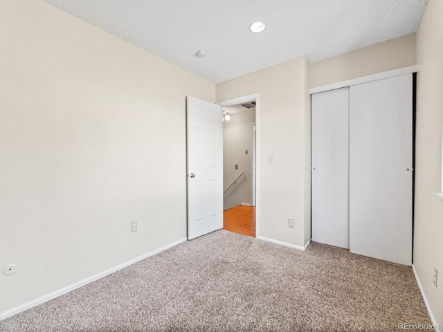 unfurnished bedroom featuring carpet flooring, a closet, and a textured ceiling