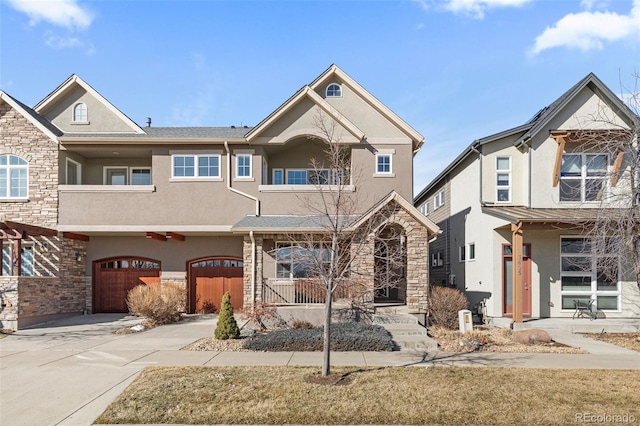 view of property with a garage, concrete driveway, stone siding, and stucco siding