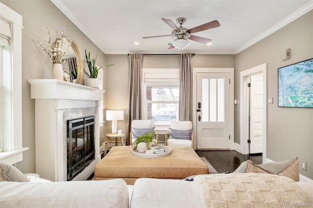 living room with baseboards, wood finished floors, crown molding, and a glass covered fireplace