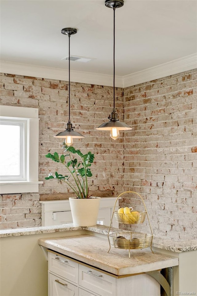 interior space featuring white cabinetry, brick wall, and ornamental molding