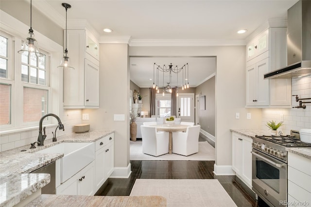 kitchen featuring white cabinets, dark wood finished floors, wall chimney exhaust hood, high end range, and a sink