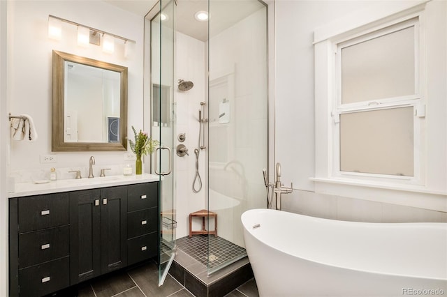 full bathroom with a shower stall, a freestanding bath, and vanity