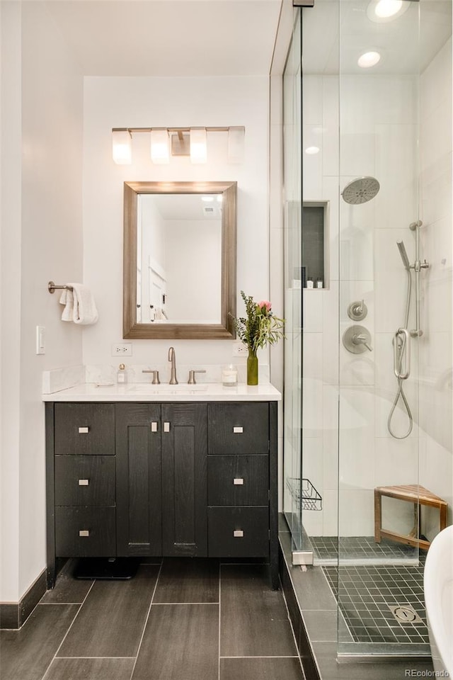 full bathroom featuring a shower stall, vanity, and baseboards