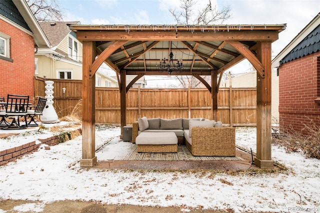 snow covered patio with outdoor lounge area, fence, and a gazebo