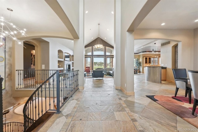 corridor with high vaulted ceiling and a notable chandelier