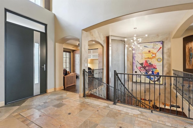 entryway featuring ceiling fan with notable chandelier