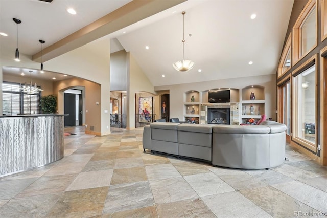 living room featuring a fireplace, built in shelves, and high vaulted ceiling