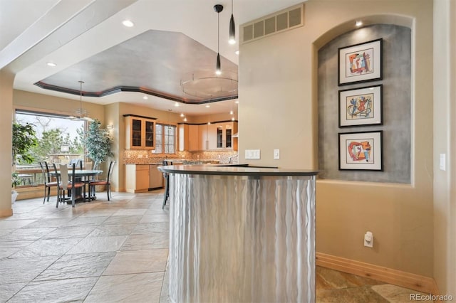 kitchen featuring kitchen peninsula, pendant lighting, backsplash, and a tray ceiling