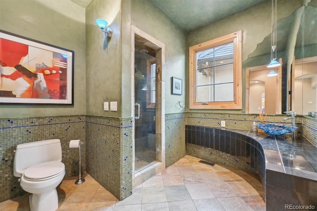 bathroom featuring an enclosed shower, toilet, sink, and tile walls