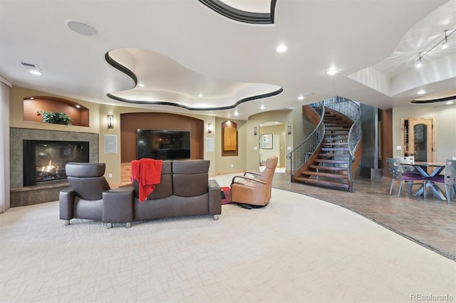 living room featuring light tile patterned floors, a tray ceiling, built in features, and a tiled fireplace