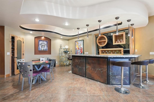 bar featuring a tray ceiling and light tile patterned floors