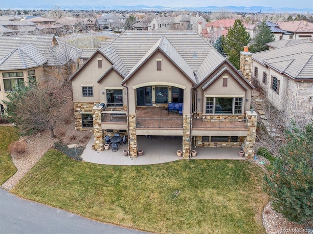 back of house featuring a lawn, a deck, and a patio