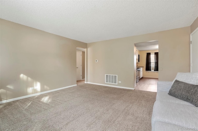 unfurnished living room featuring a textured ceiling and light carpet