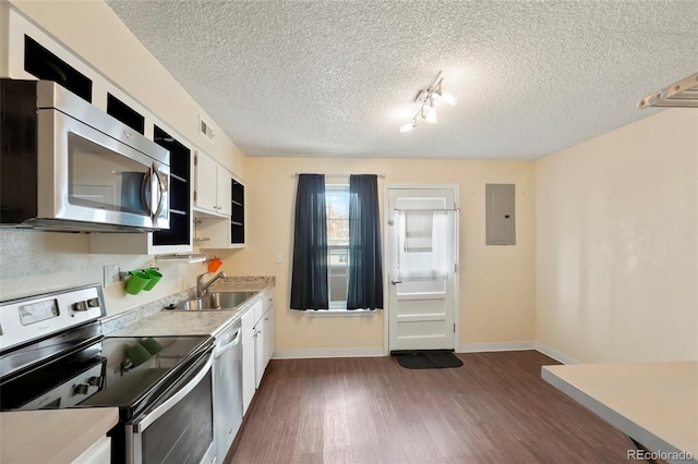 kitchen with electric panel, appliances with stainless steel finishes, sink, white cabinets, and dark wood-type flooring