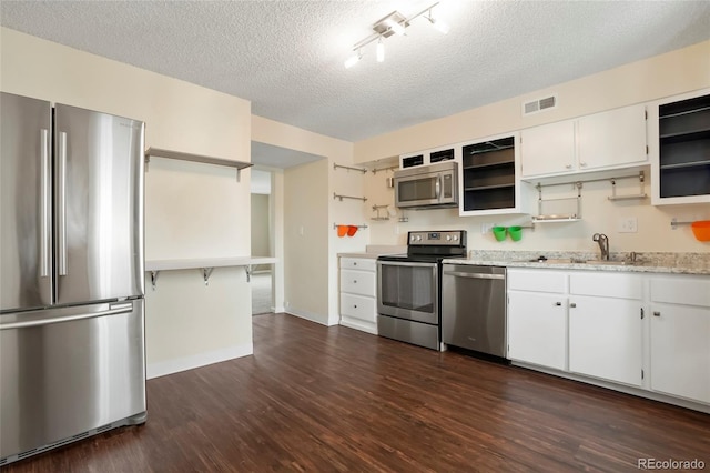 kitchen with white cabinets, appliances with stainless steel finishes, dark wood-type flooring, and a textured ceiling