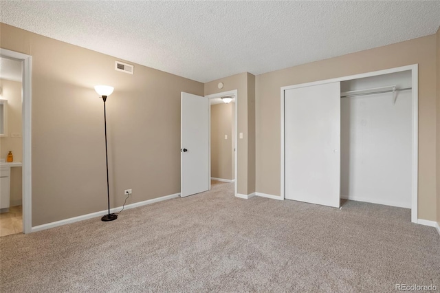 unfurnished bedroom featuring a closet, a textured ceiling, and light colored carpet