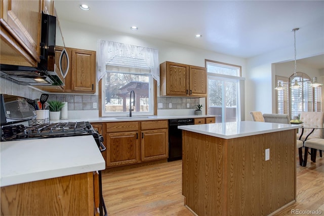 kitchen with decorative backsplash, black dishwasher, a center island, and sink