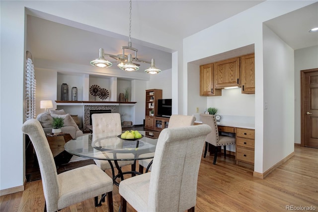 dining area with light wood-type flooring and a tiled fireplace