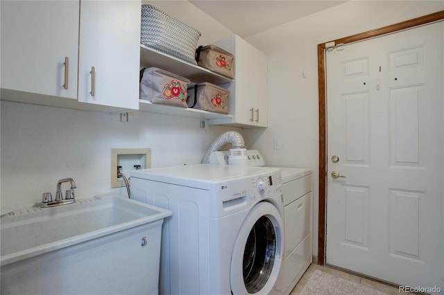 clothes washing area featuring cabinets, washing machine and clothes dryer, and sink