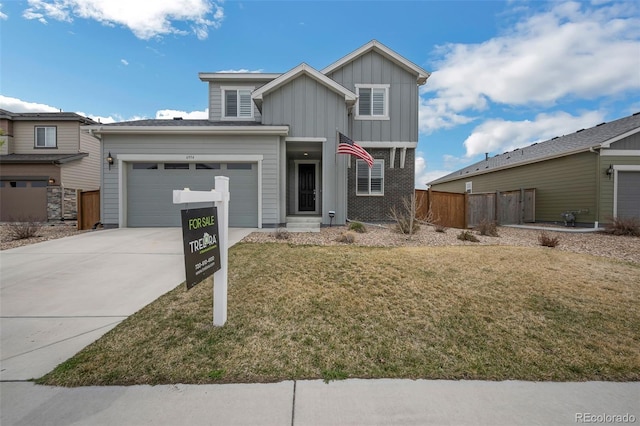 view of front of house with fence, board and batten siding, driveway, a front yard, and a garage