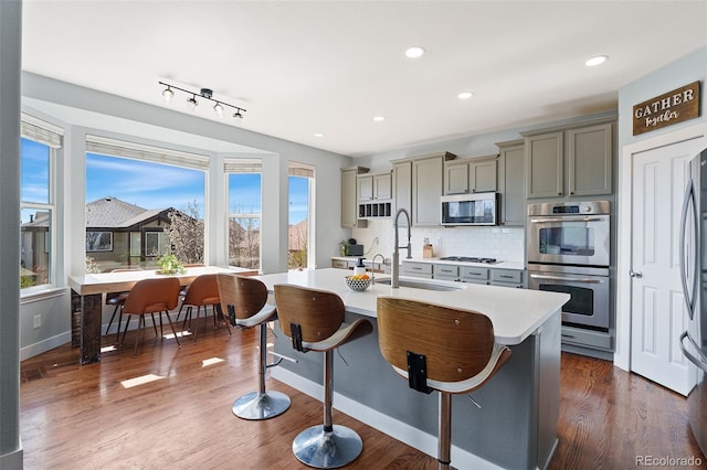 4464 E 139th Ave, Thornton, CO 80602 - kitchen with stainless steel appliances, light countertops, an island with sink, a kitchen bar, and a sink
