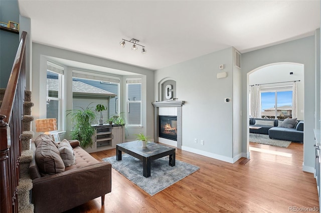 4464 E 139th Ave, Thornton, CO 80602 - living room with a tile fireplace, light wood-style floors, baseboards, and arched walkways