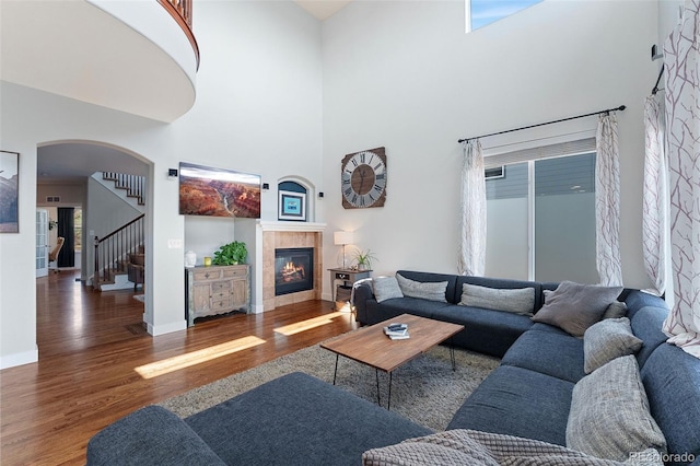 4464 E 139th Ave, Thornton, CO 80602 - living area with wood finished floors, a fireplace, a towering ceiling, arched walkways, and stairway