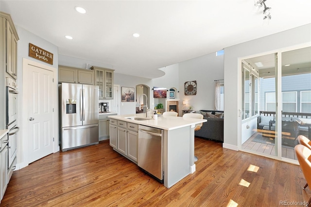 4464 E 139th Ave, Thornton, CO 80602 - kitchen featuring appliances with stainless steel finishes, a sink, open floor plan, arched walkways, and light wood finished floors