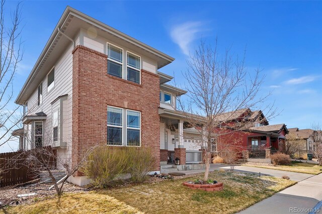 4464 E 139th Ave, Thornton, CO 80602 - view of front facade with covered porch, a front yard, and brick siding