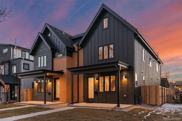 rear view of house featuring a yard, brick siding, and board and batten siding