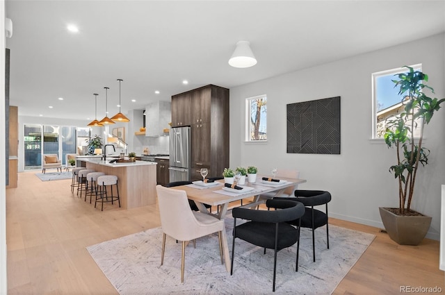 dining space with light wood-type flooring, a wealth of natural light, and sink