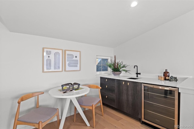 kitchen with sink, wine cooler, light hardwood / wood-style floors, and dark brown cabinetry