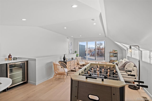 game room featuring bar, wine cooler, light hardwood / wood-style floors, and vaulted ceiling with beams