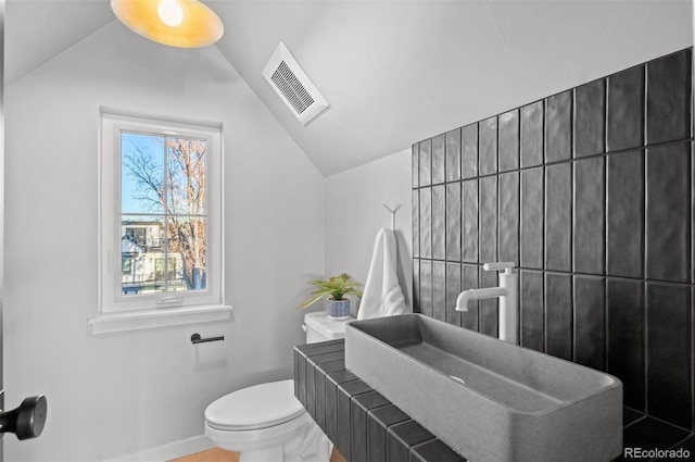 bathroom with sink, toilet, and lofted ceiling