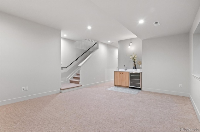 bar featuring light brown cabinetry, beverage cooler, light carpet, and sink