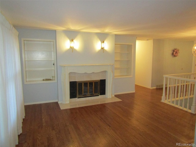 unfurnished living room with dark hardwood / wood-style floors, built in features, and a fireplace