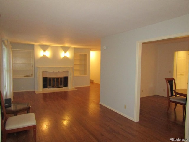 living room featuring built in shelves and dark hardwood / wood-style flooring