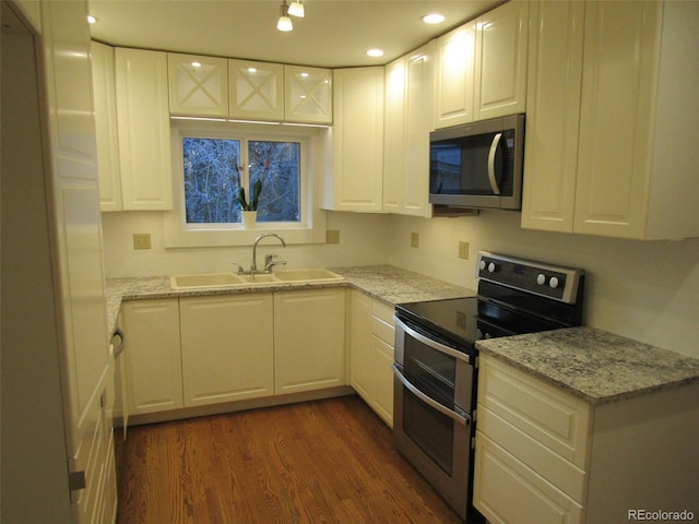 kitchen with white cabinets, sink, appliances with stainless steel finishes, dark hardwood / wood-style flooring, and light stone counters