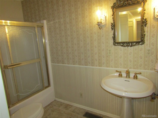 bathroom with shower / bath combination with glass door, tile patterned flooring, and toilet