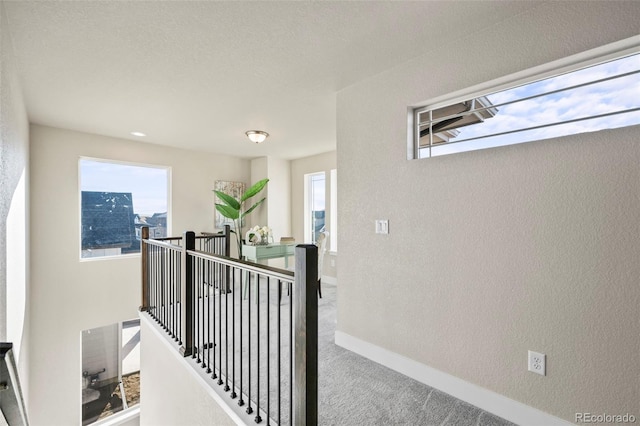 corridor with carpet floors, plenty of natural light, an upstairs landing, and baseboards