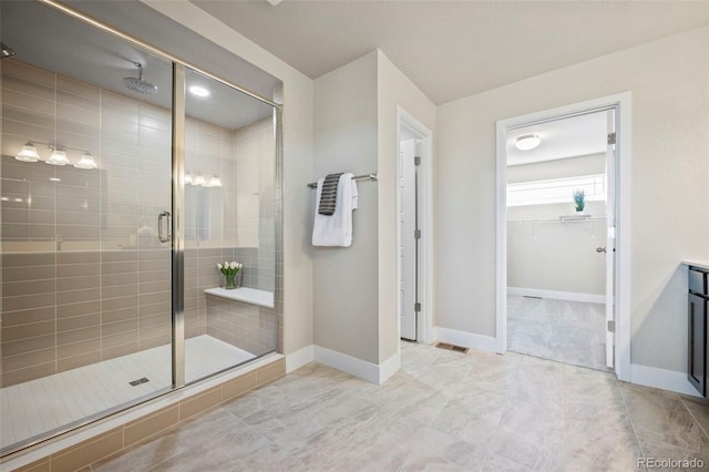 bathroom with visible vents, baseboards, a shower stall, tile patterned floors, and a walk in closet