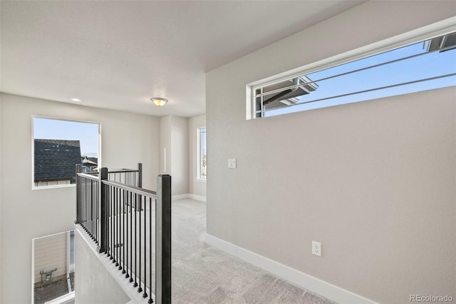 hallway featuring baseboards, carpet flooring, and an upstairs landing