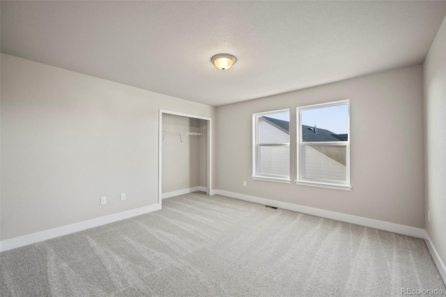 unfurnished bedroom featuring carpet, a closet, visible vents, a textured ceiling, and baseboards