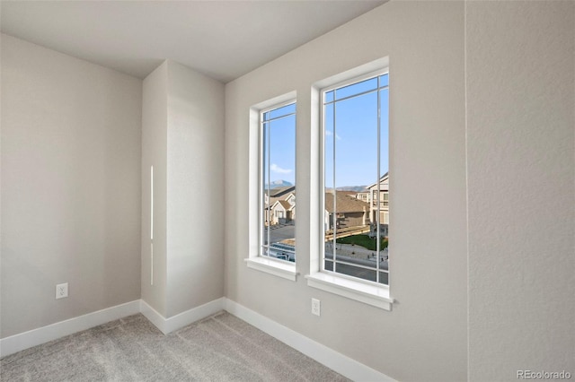 unfurnished room with light colored carpet and baseboards