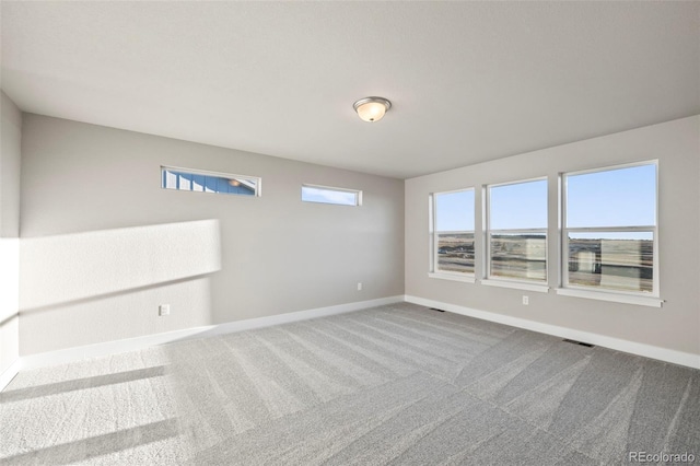 carpeted spare room featuring visible vents and baseboards